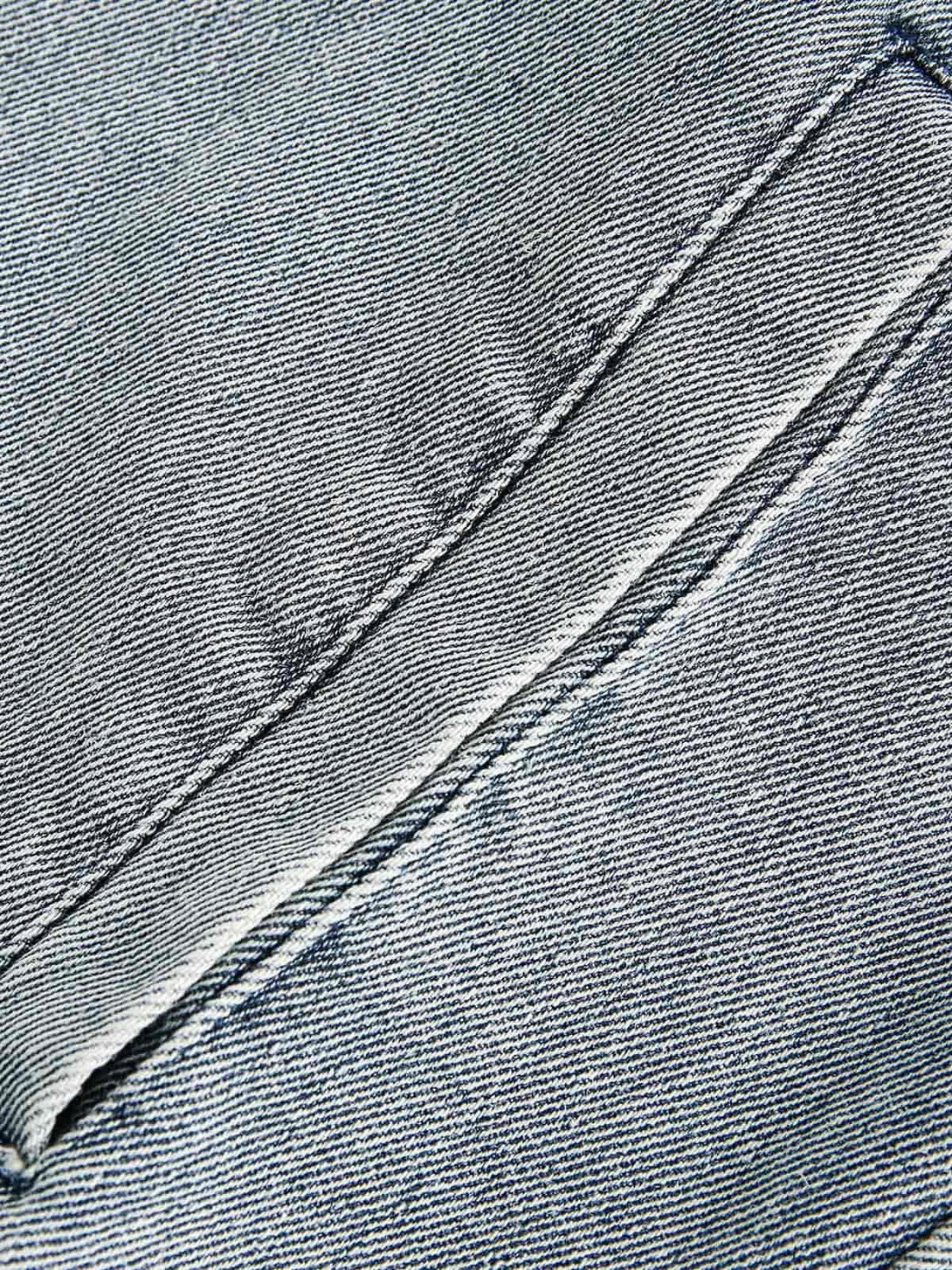 Detailed fabric and stitching on TALISHKO's denim jacket, highlighting the unique texture.