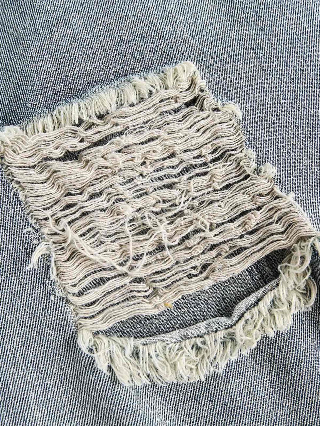 Zoomed-in texture of the ripped lace panel on a TALISHKO denim jacket, highlighting unique design.