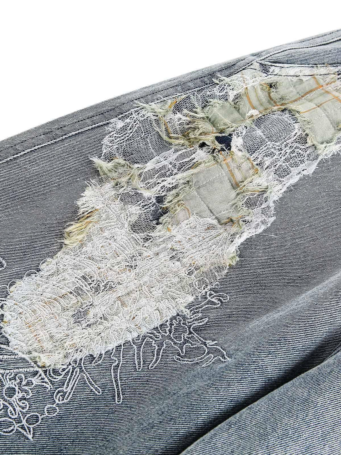 Intricate look at the ripped lace detailing on TALISHKO's denim pants, showcasing unique texture.