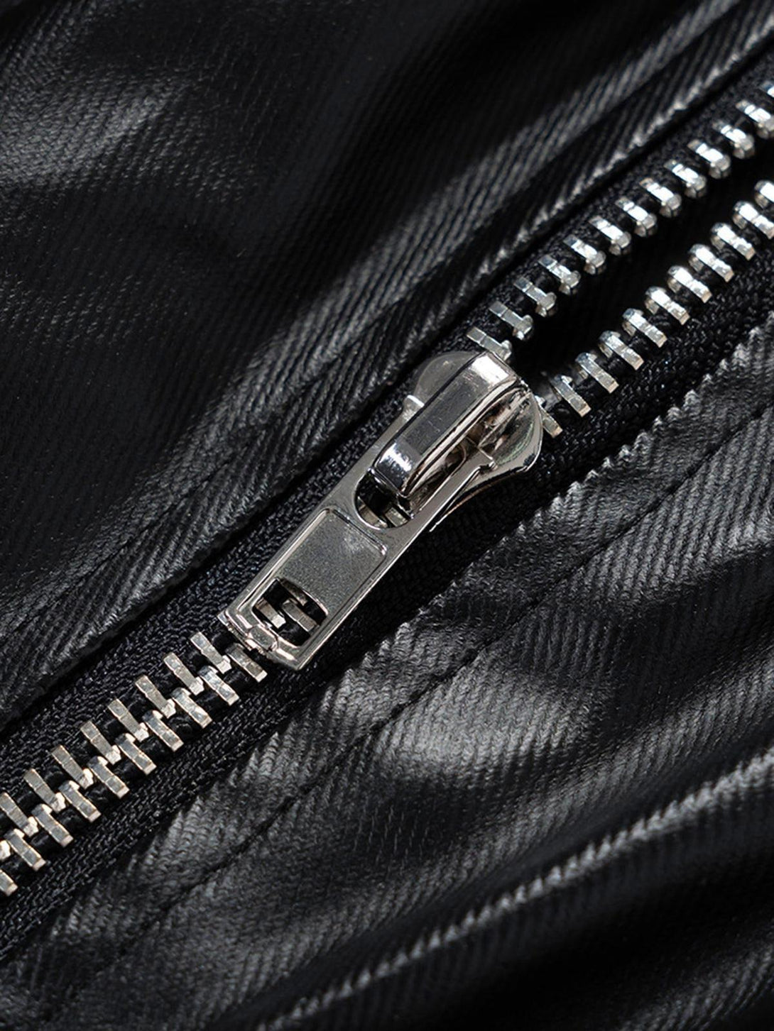 A detailed look at TALISHKO overalls focusing on the shiny metal zipper and matte-coated fabric.