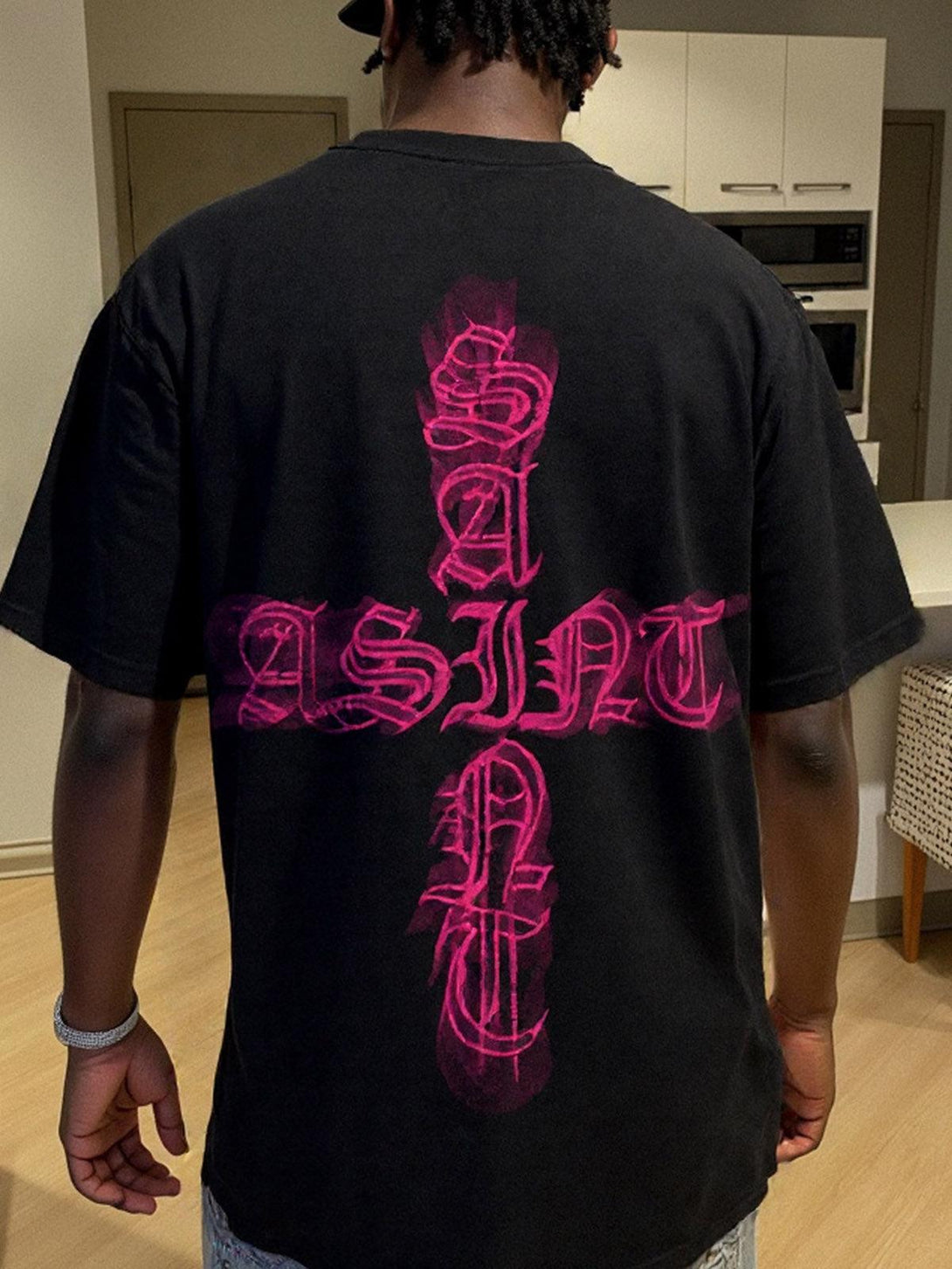 Back view of TALISHKO "SAINT" graphic T-shirt in black, featuring a bold pink design.
