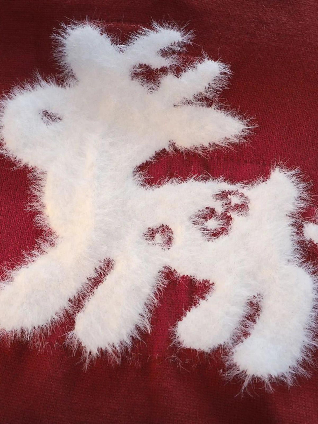 A detailed look at TALISHKO's red sweater, highlighting the fluffy white sika deer motif.