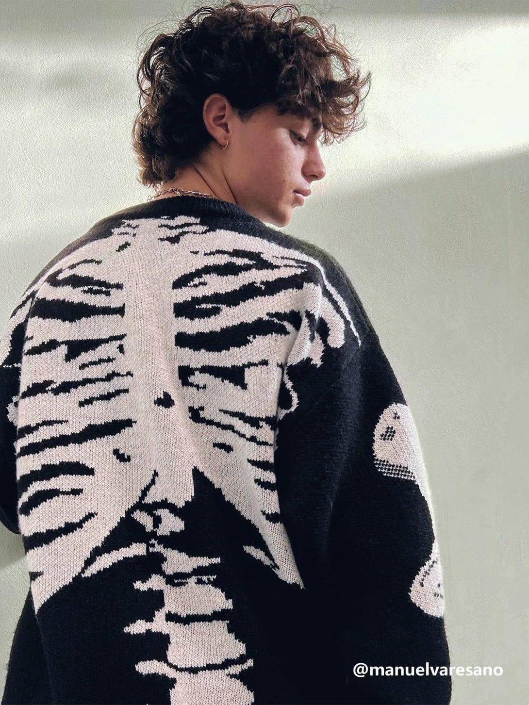 Person models TALISHKO's skeleton pattern knit sweater, highlighting its edgy back design.