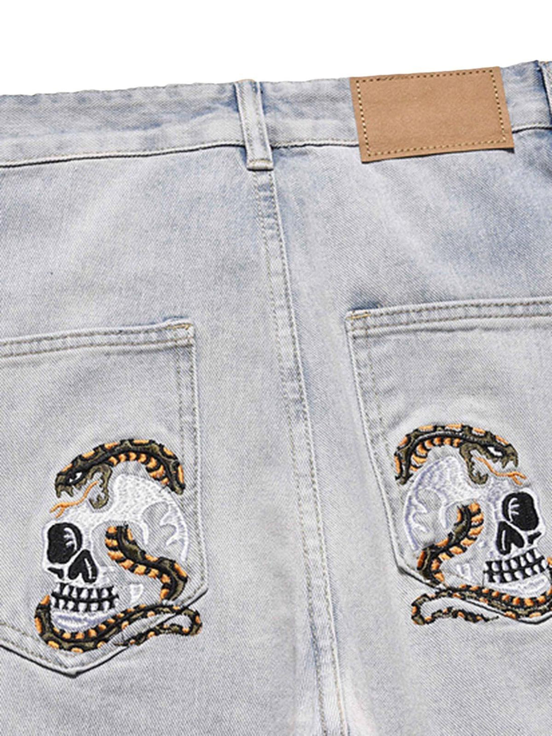 Back detail of TALISHKO jeans featuring skull and snake embroidery on light denim pockets.
