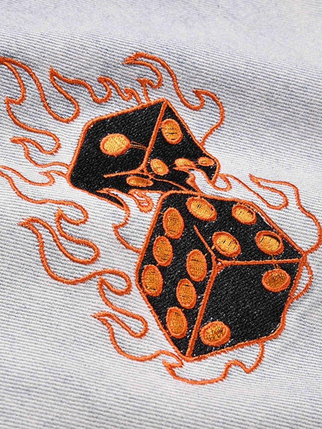 A detailed view of TALISHKO jeans' fiery dice embroidery, showcasing bold orange stitching.