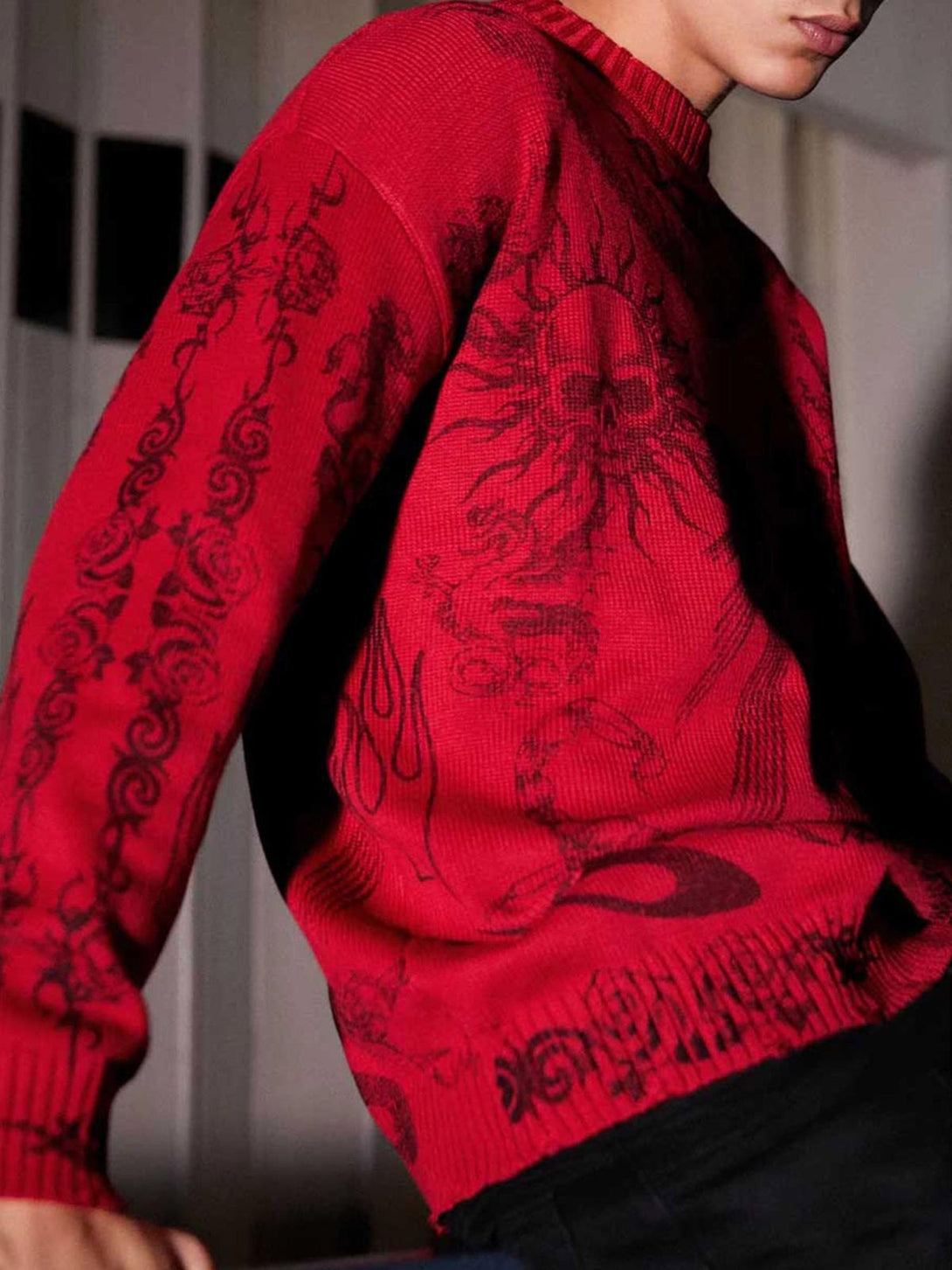 Model in a red TALISHKO sweater with skull and sun motifs, capturing a bold, edgy vibe.