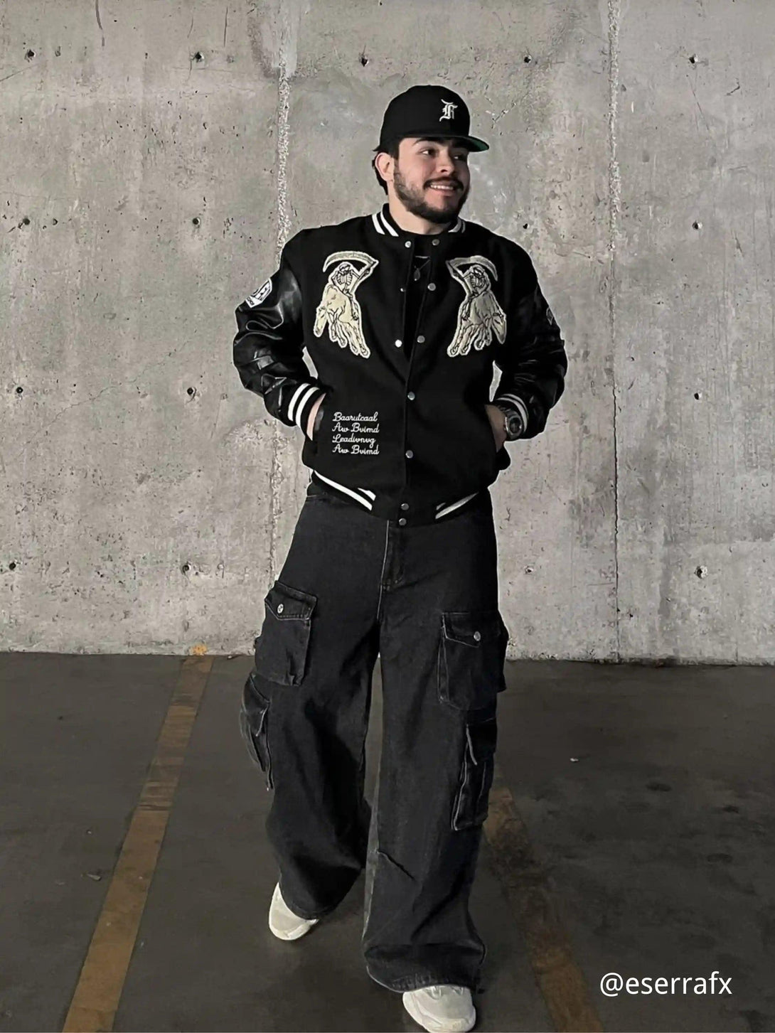 A model wearing a TALISHKO jacket with skull embroidery and PU sleeves, styled with cargo pants.