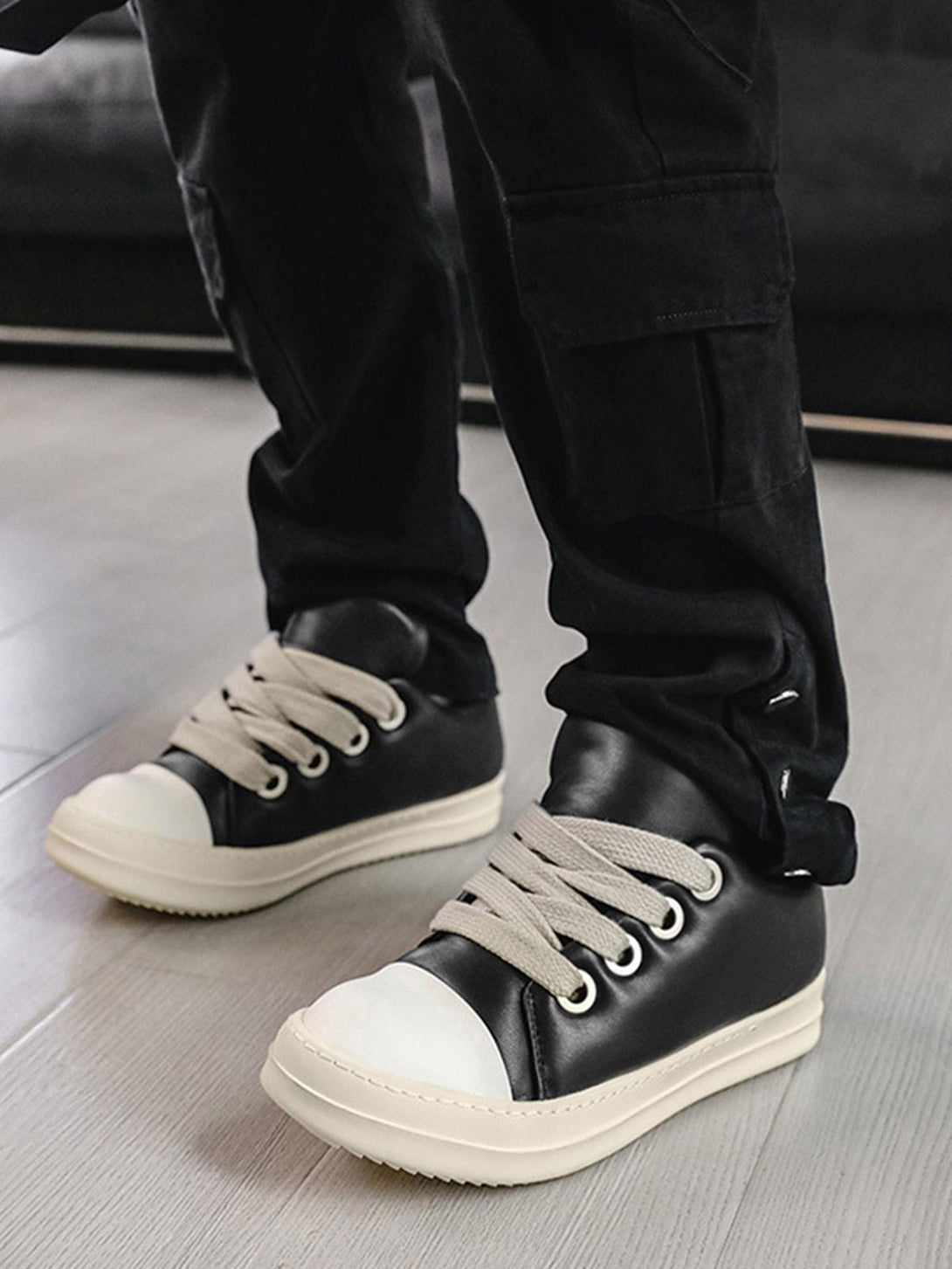 Stylish black and white sneakers by TALISHKO with wide laces, adding a trendy touch to casual wear.