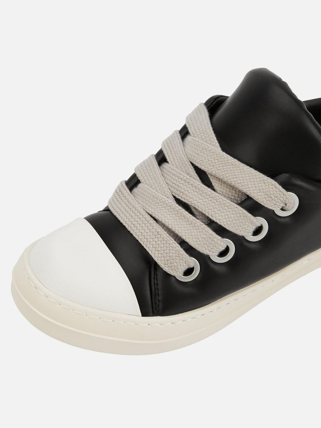 A close-up of TALISHKO slip-on sneakers showcasing wide laces and sleek black and white design.