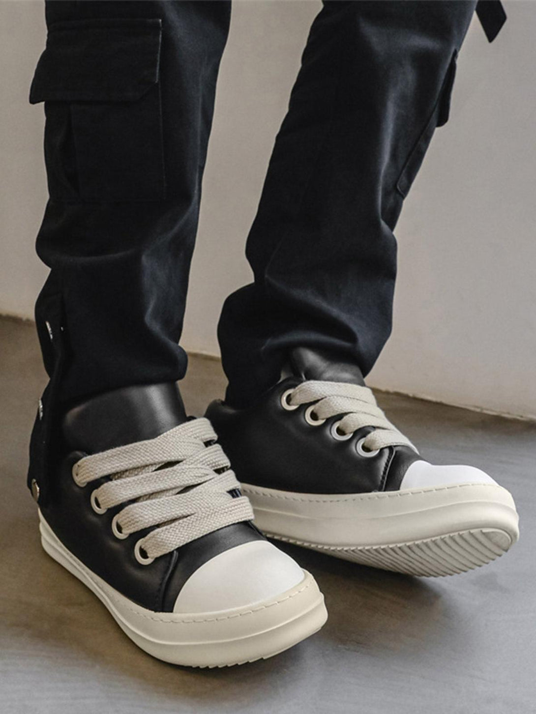 Black and white TALISHKO sneakers with wide laces, perfect for adding flair to casual looks.