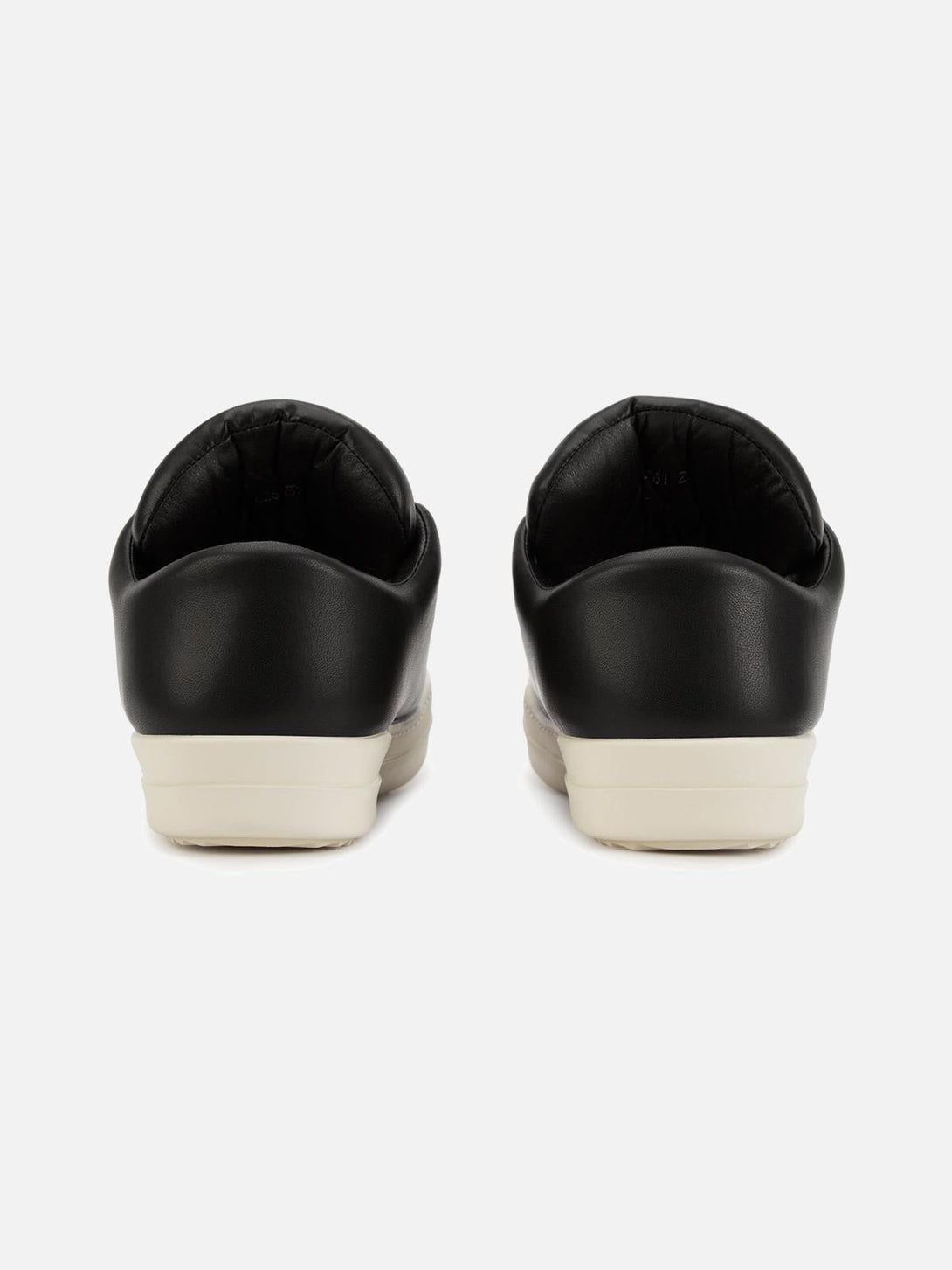 Rear view of TALISHKO slip-on sneakers featuring sleek black design and contrasting white soles.