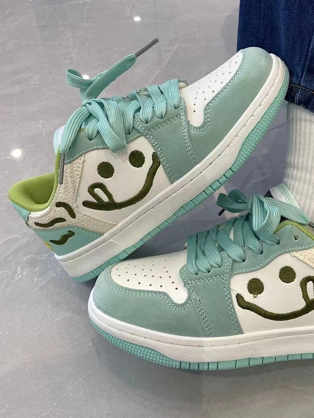 TALISHKO smiley skateboarding shoes in mint green, paired with denim for a playful look.
