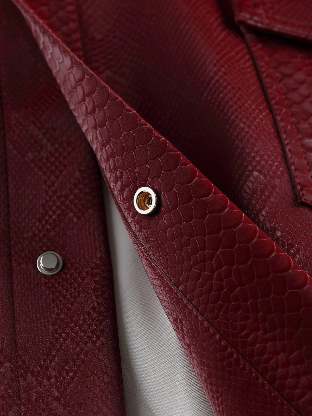 Detailed fabric and stitching of TALISHKO's red snake texture faux leather jacket.