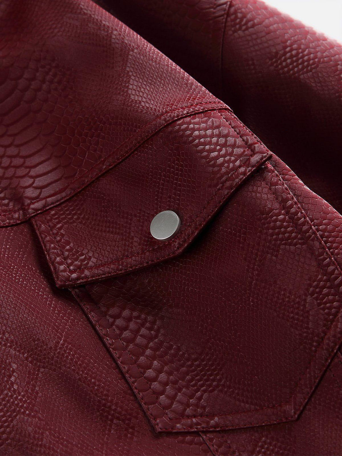 Intricate look at red snake texture with silver button detail on TALISHKO faux leather jacket.