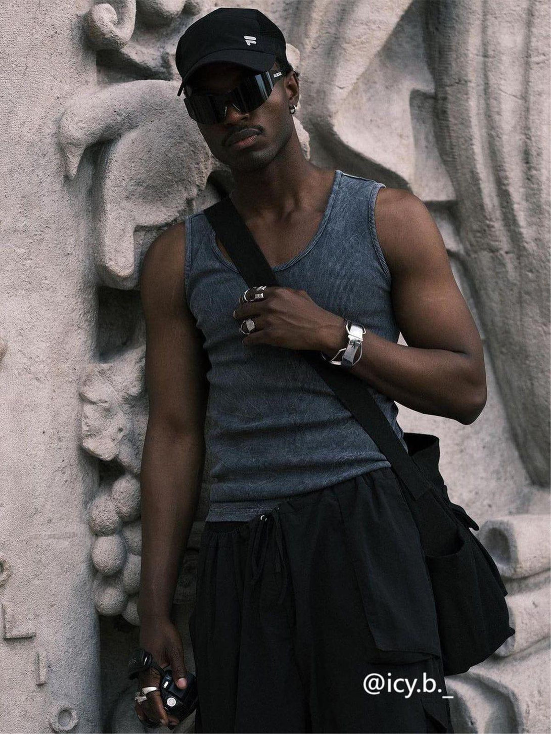 Man wearing a casual tank top and black shoulder bag by TALISHKO, exuding urban style.