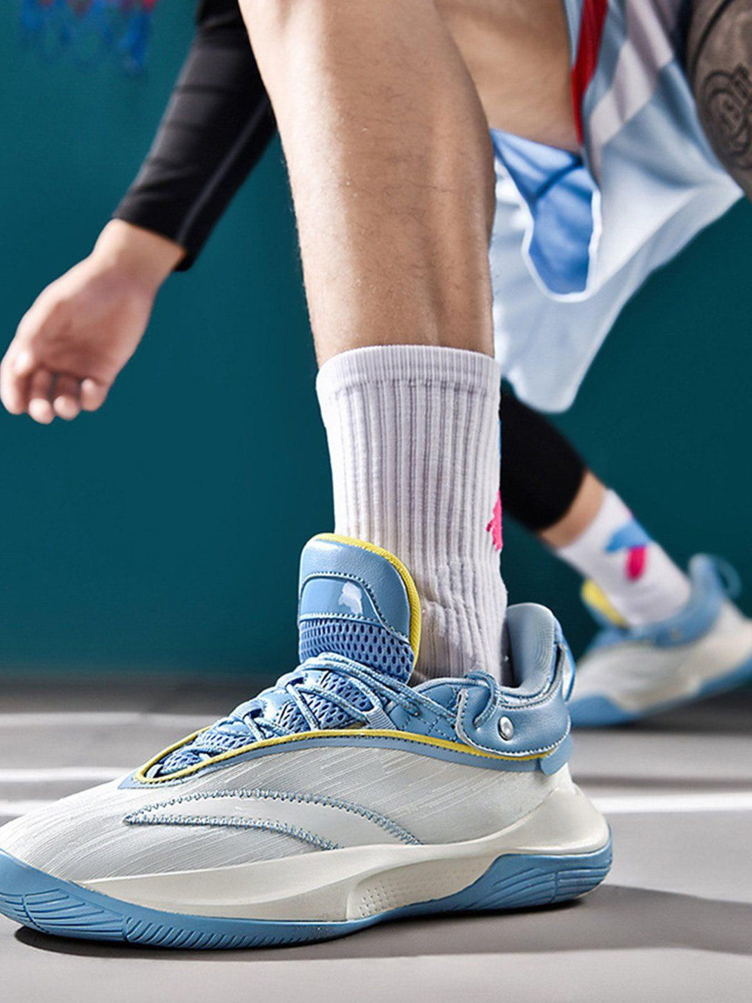 TALISHKO breathable sneakers in blue and white, worn during an active moment on the court.