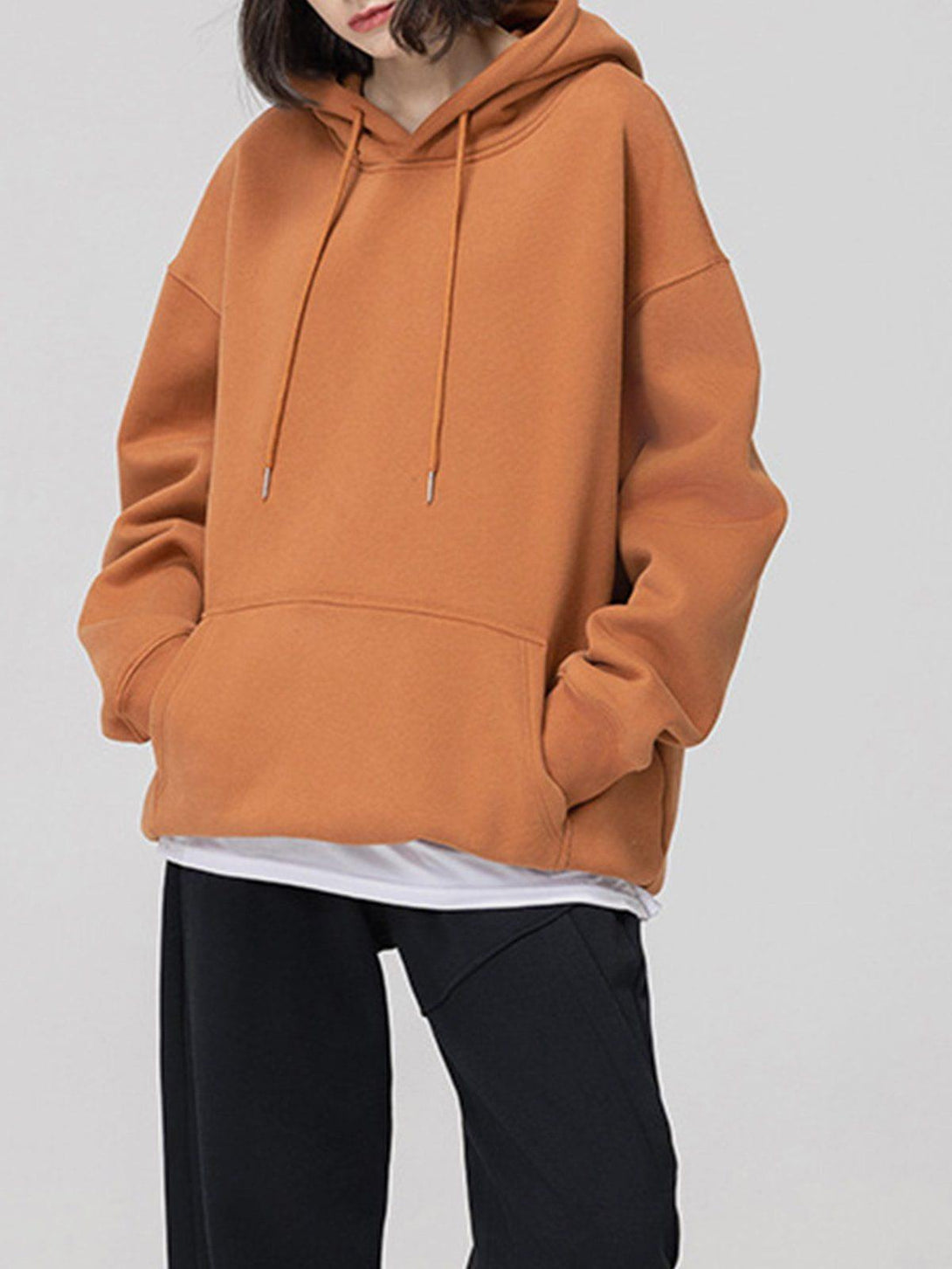 Model in a cinnamon drawstring hoodie by TALISHKO, highlighting a laid-back street style.