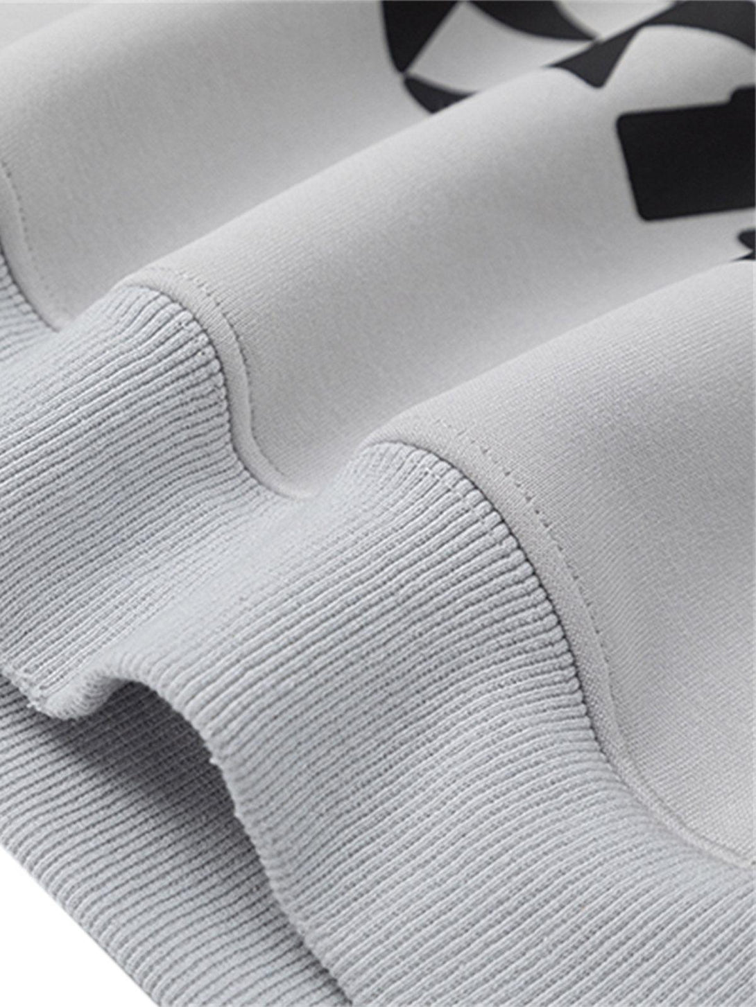 Textured gray fabric and ribbed hem of TALISHKO racing hoodie, showcasing quality details.