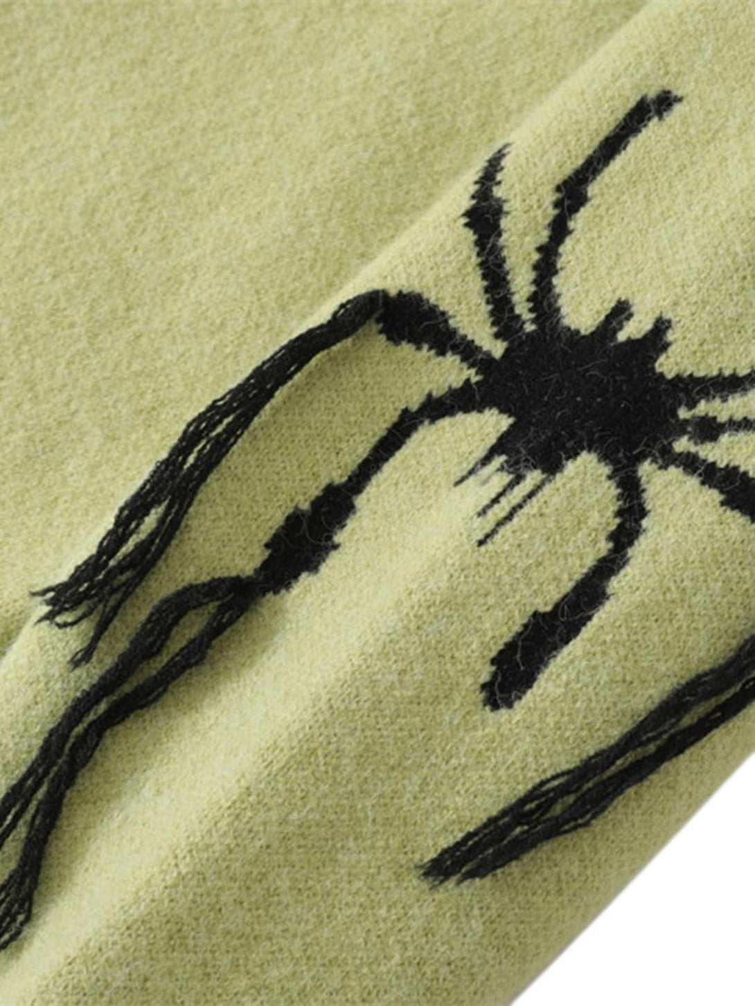 Zoomed-in texture of TALISHKO's green sweater, highlighting distressed spider design details.