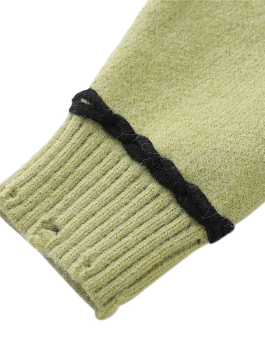 A close-up of TALISHKO's green sweater cuff, highlighting ribbed texture and black trim detail.