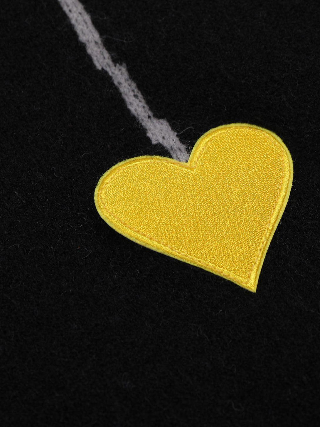A close-up of a yellow heart detail on TALISHKO's knit sweater, showcasing intricate stitching.