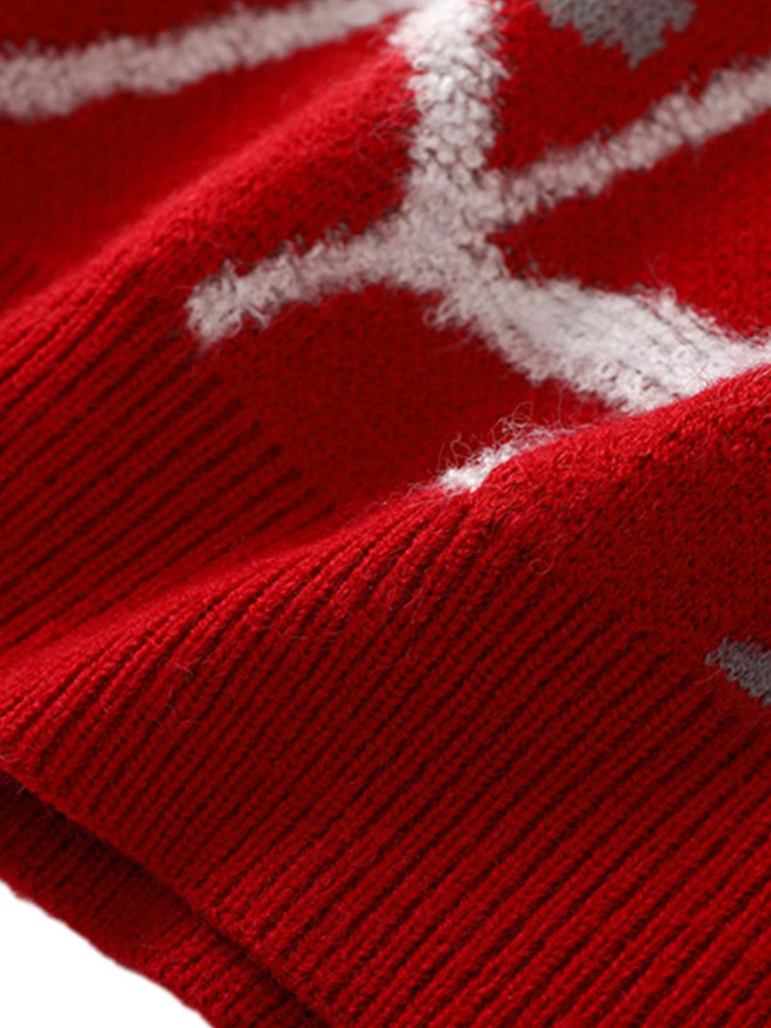 A detailed view of TALISHKO's red knit sweater, highlighting its intricate pattern and texture.