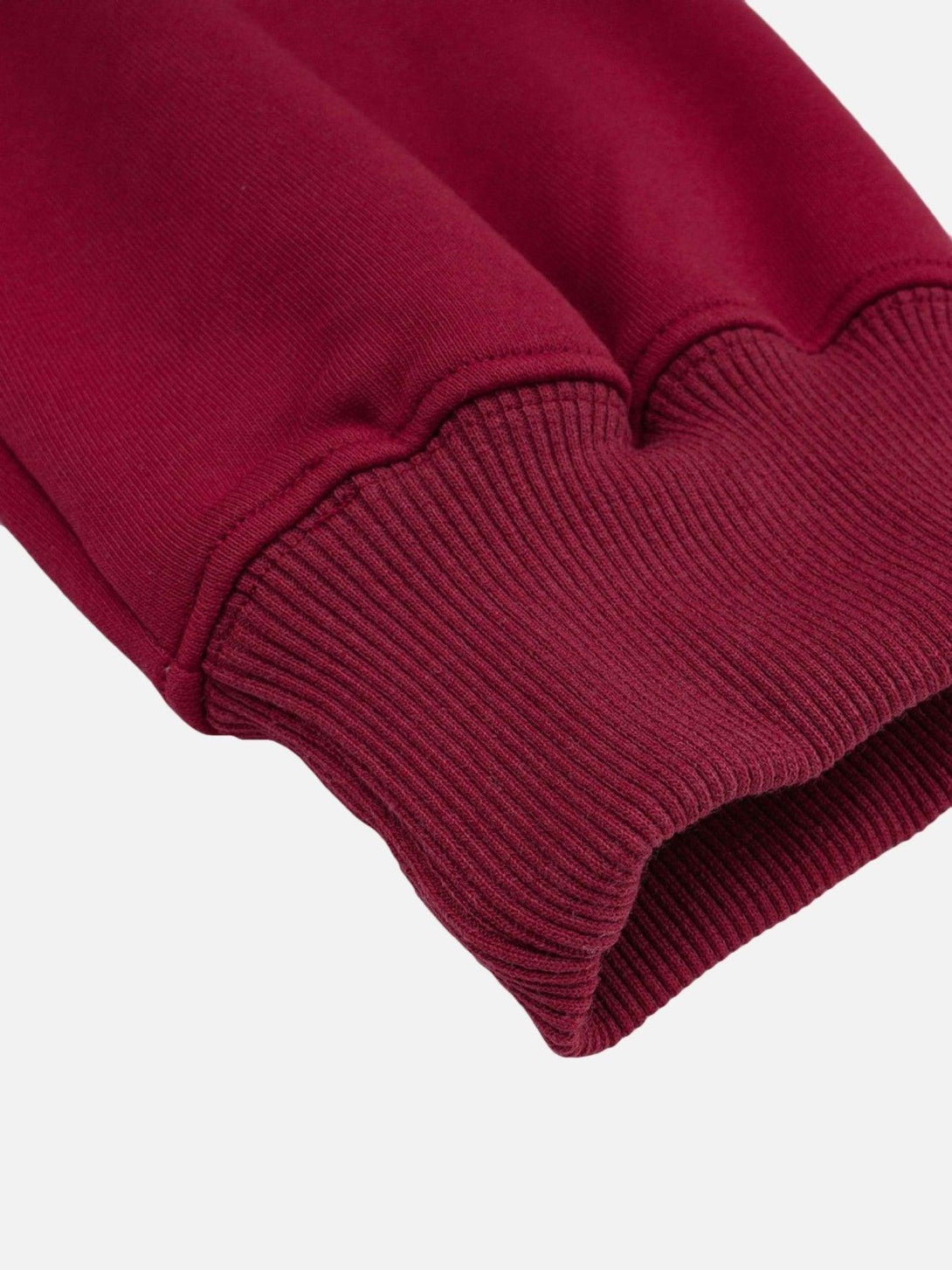 A close-up of TALISHKO's red hoodie sleeve, highlighting its ribbed cuff detail.