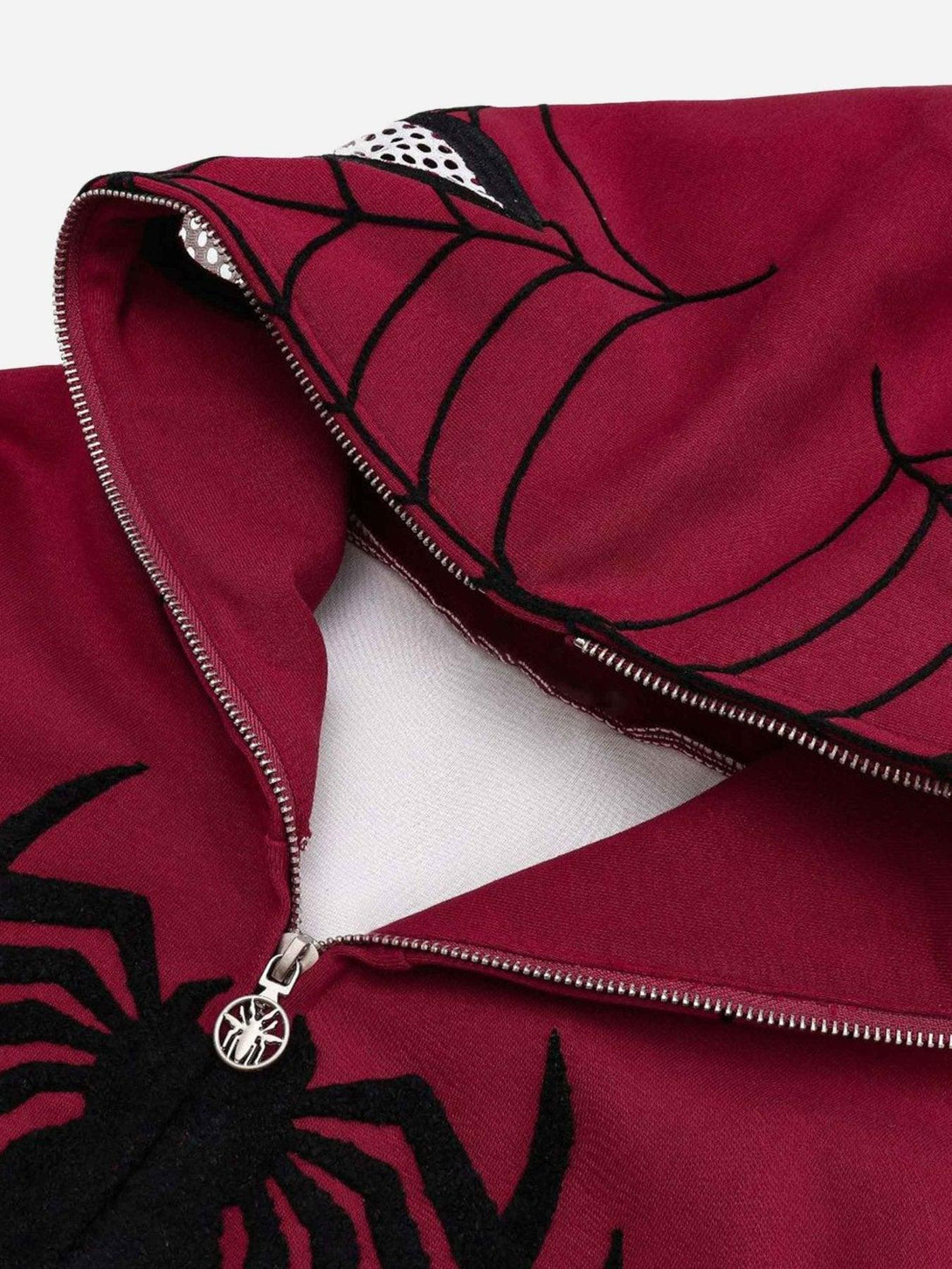 Intricate look at TALISHKO's spider web embroidery on a red hoodie, highlighting unique details.