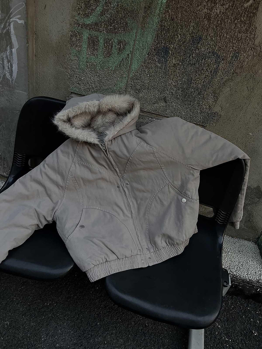 Fur-lined hooded jacket by TALISHKO draped over a chair, showcasing casual urban style.