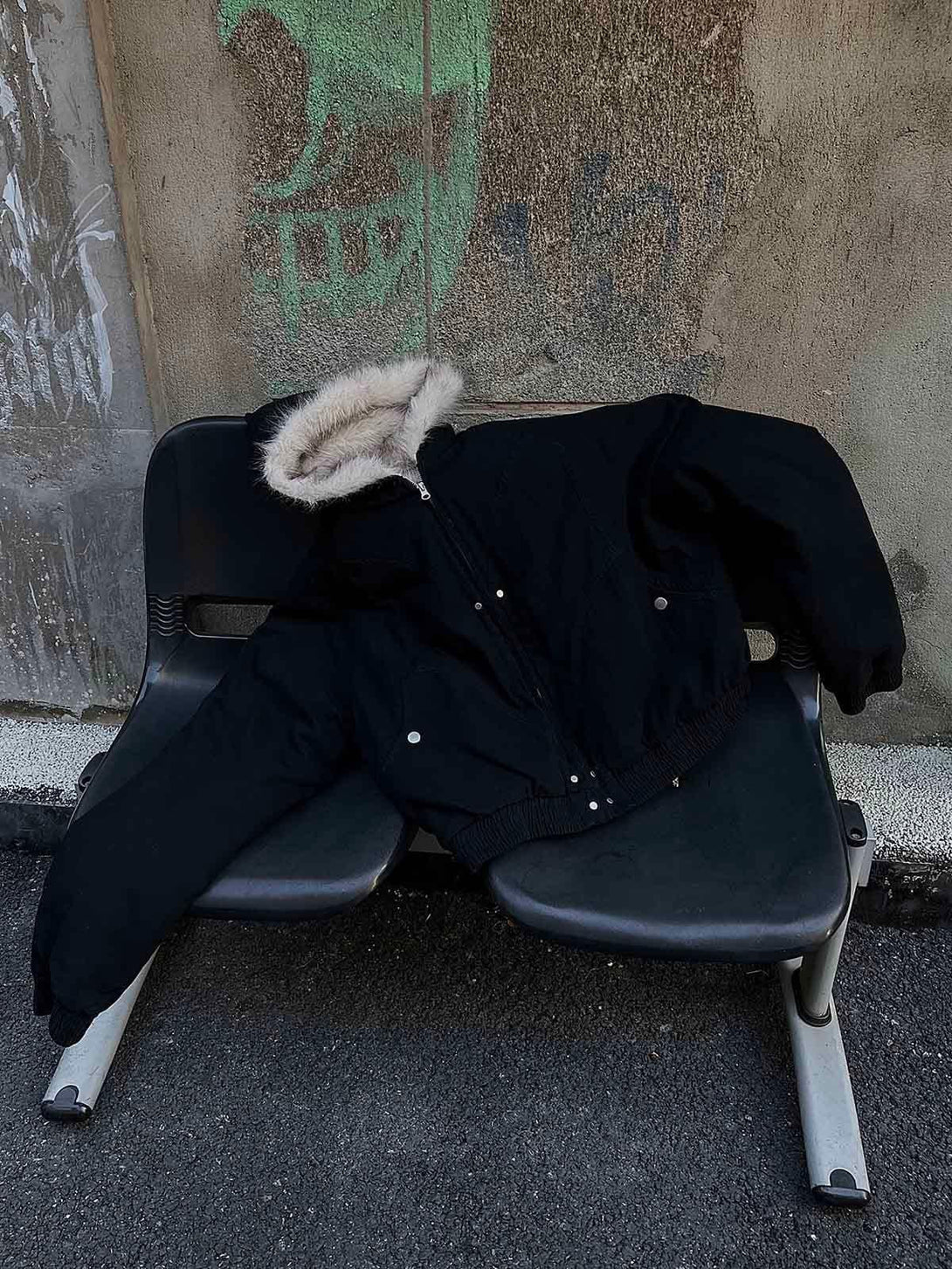 TALISHKO's black quilted jacket with fur hood draped on a chair, capturing laid-back style.