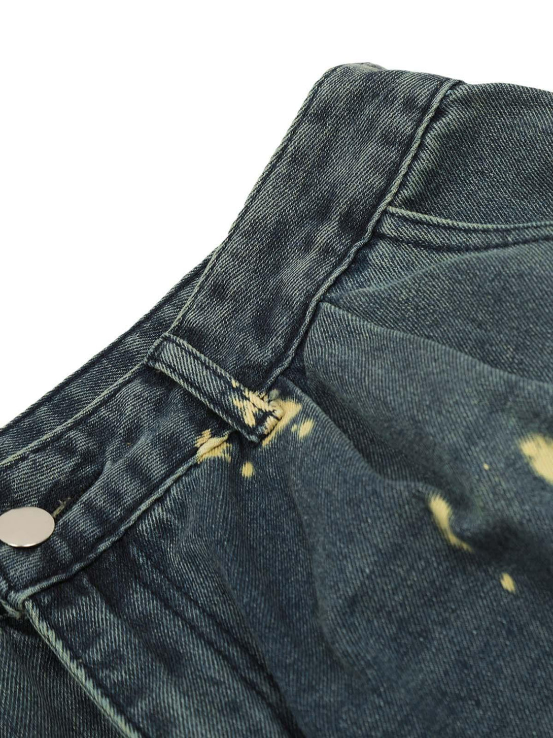 Intricate look at spray-painted pleated detail on TALISHKO cargo jeans, highlighting unique texture.
