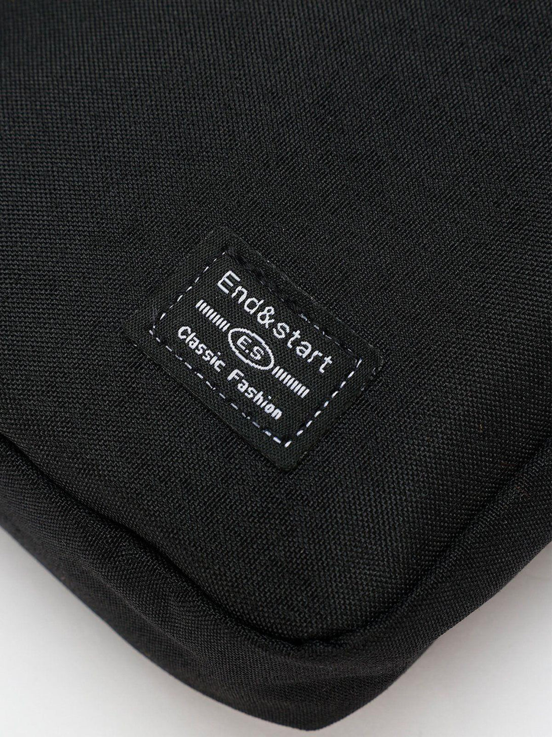 Intricate look at TALISHKO's black square crossbody bag, showcasing detailed fabric and stitching.