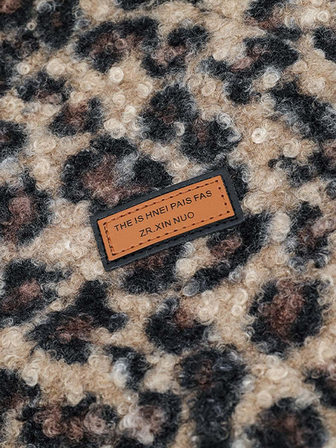 Intricate look at TALISHKO's fleece jacket showcasing its cheetah print texture and label detail.