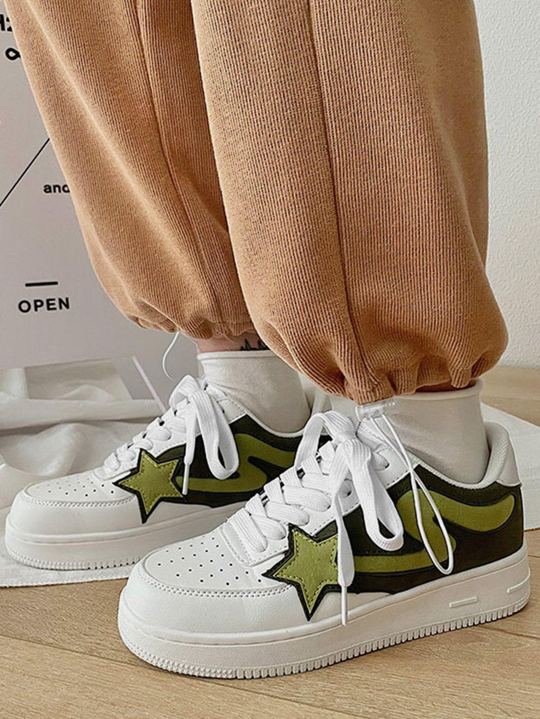 Casual sneakers with green star accents by TALISHKO, paired with cozy brown pants.