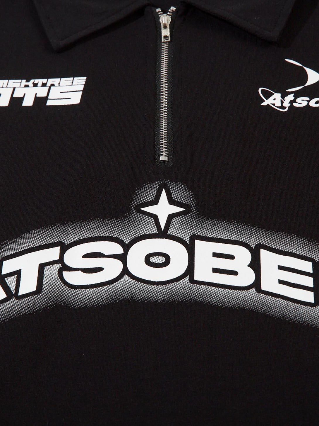 A close-up of TALISHKO's black quarter zipper shirt, highlighting star graphics and zipper detail.
