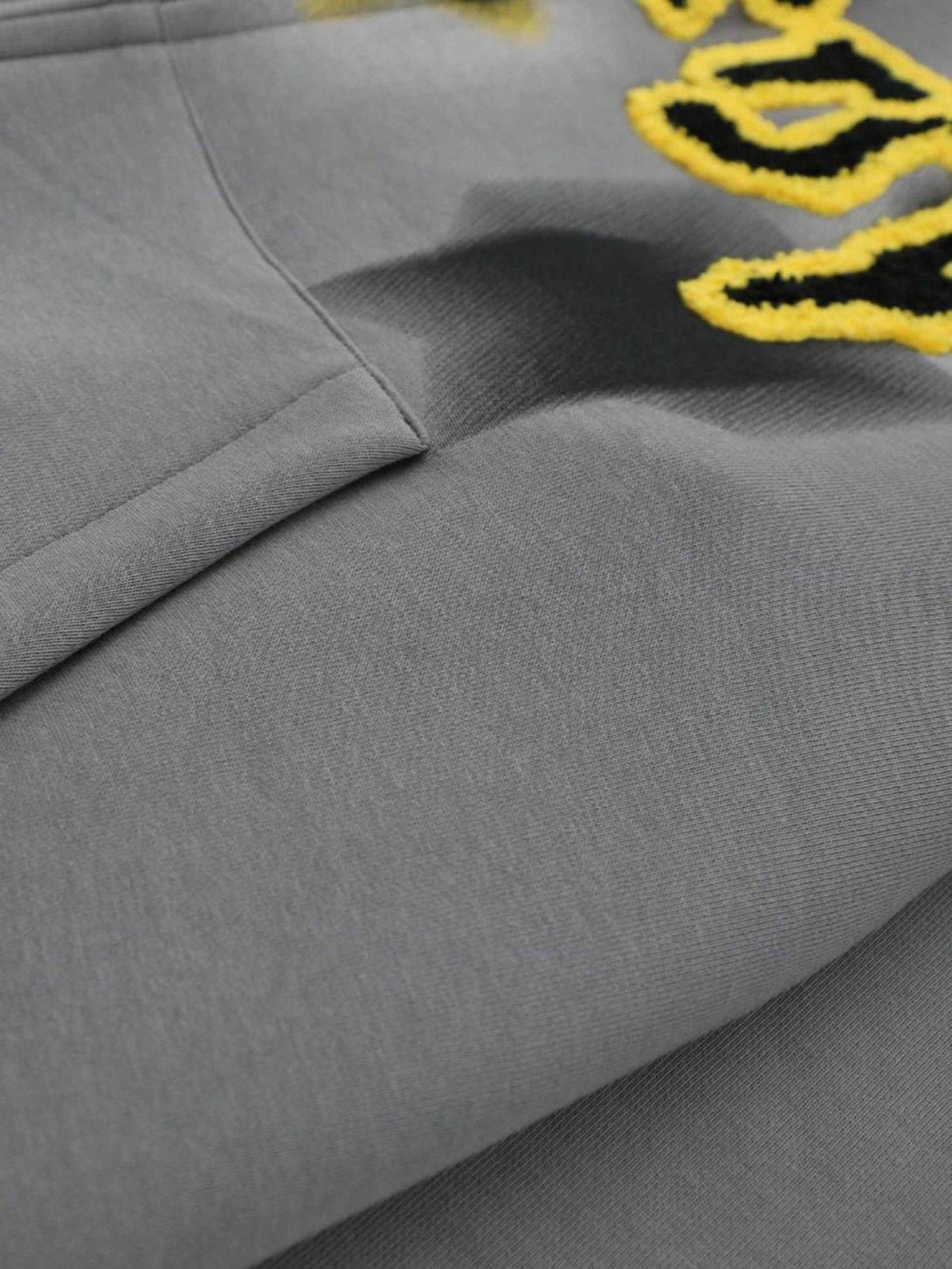 Zoomed-in texture of TALISHKO sweatshirt highlighting yellow star embroidery and fabric detail.