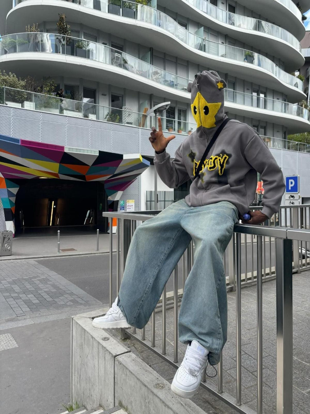 Person wearing TALISHKO star-embroidered hooded sweatshirt, sitting casually on a railing.