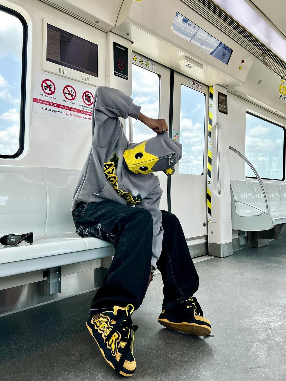 Person wearing TALISHKO star-embroidered hoodie, seated on a train, exuding urban flair.