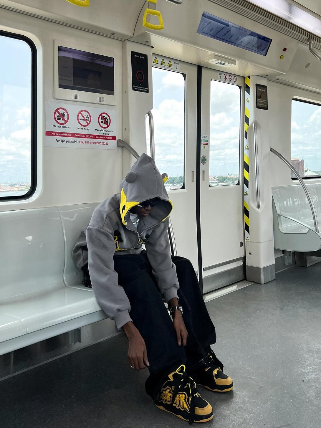 Person wearing TALISHKO star-embroidered hoodie, seated in a train, exuding casual style.