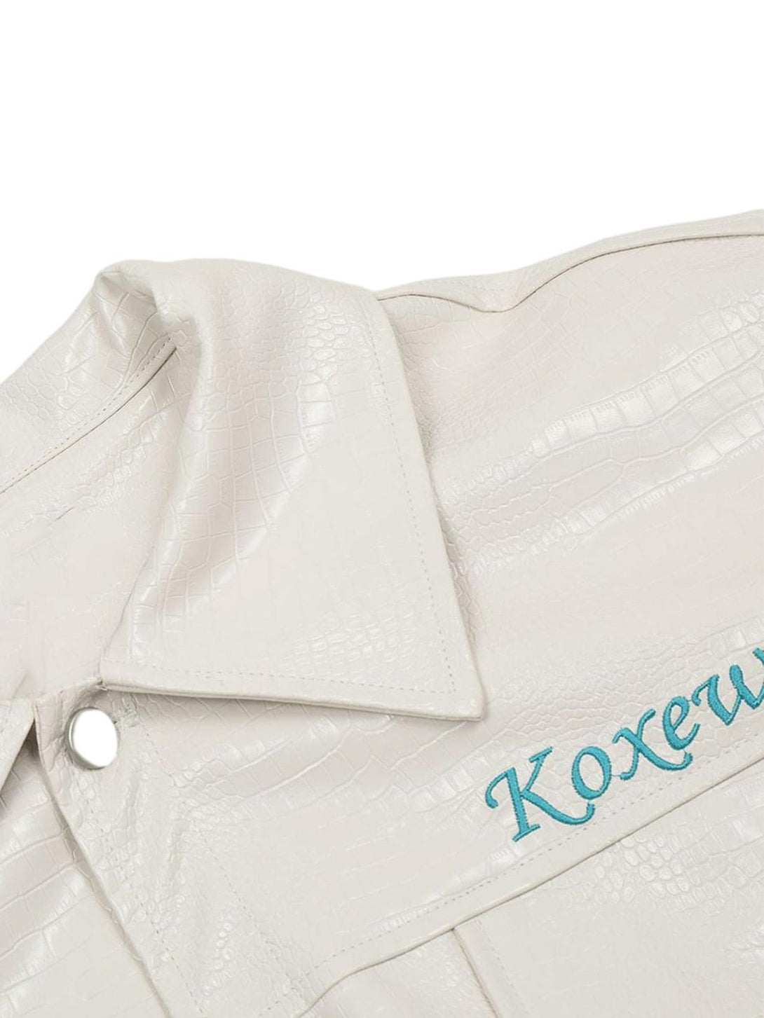 A detailed view of the TALISHKO white PU leather jacket with textured pattern and blue embroidery.