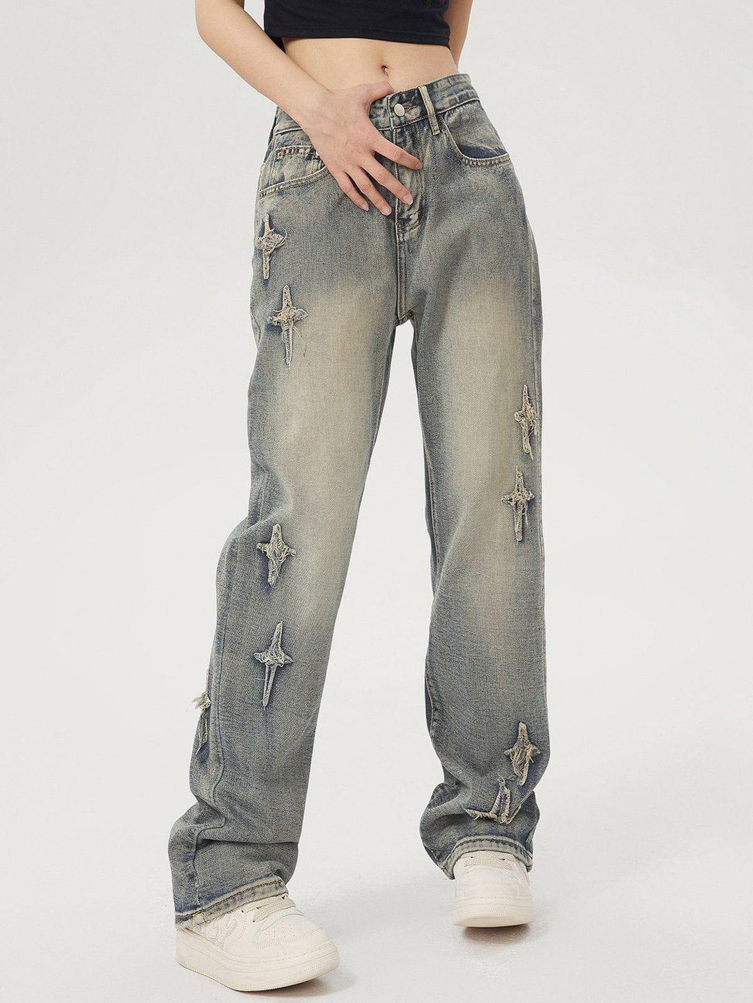 Model showcasing star embroidered washed jeans by TALISHKO, paired with casual sneakers.