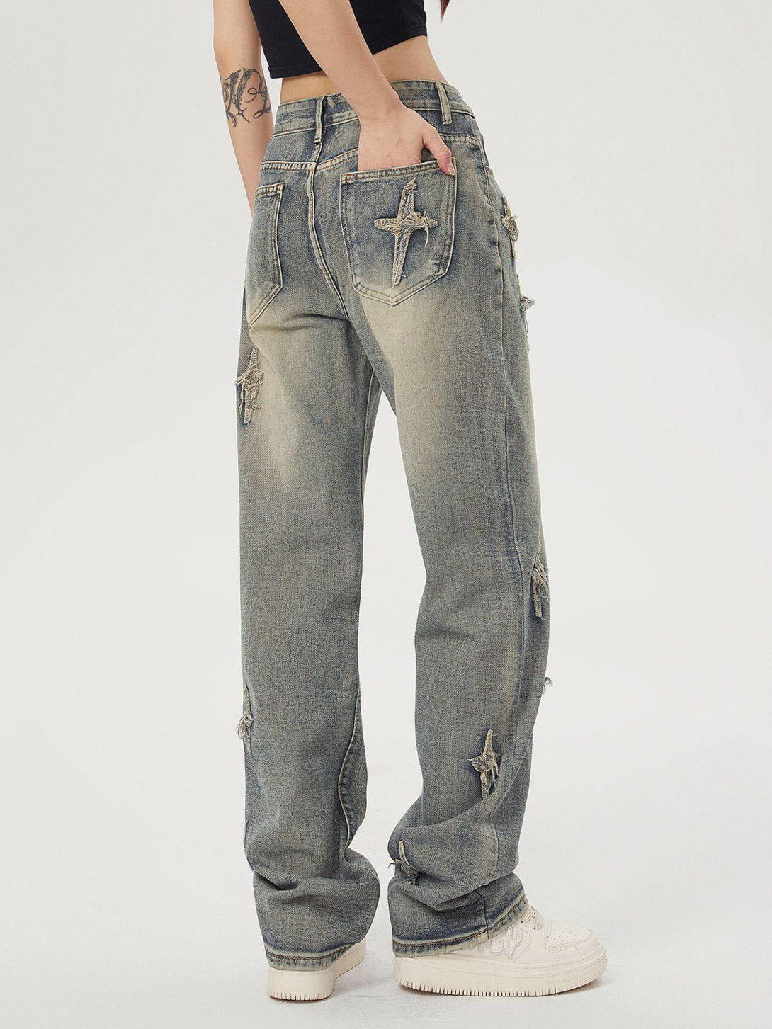 Model in TALISHKO star embroidered washed jeans from the back, accentuating casual style.