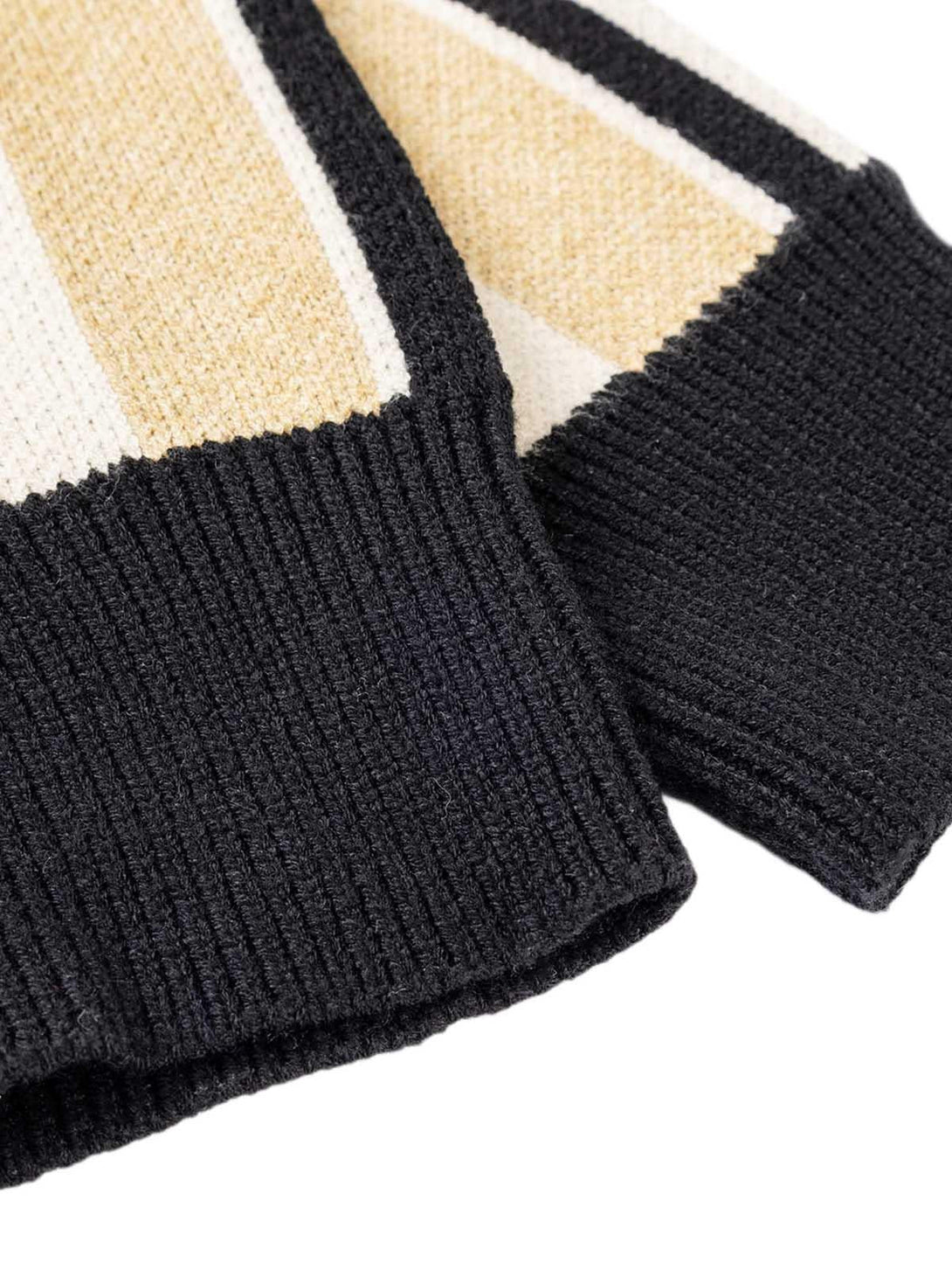 A detailed view of TALISHKO's striped sweater cuffs, showcasing bold knit texture and contrast.