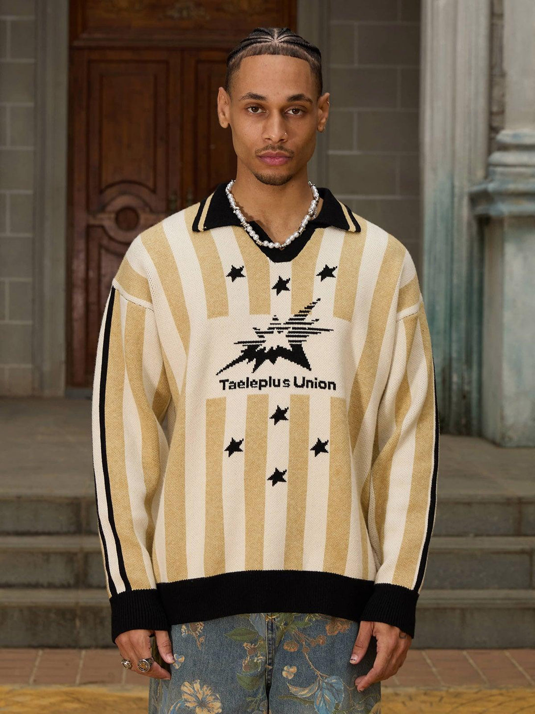 Model wearing a striped sweater with star details by TALISHKO, styled with floral jeans.