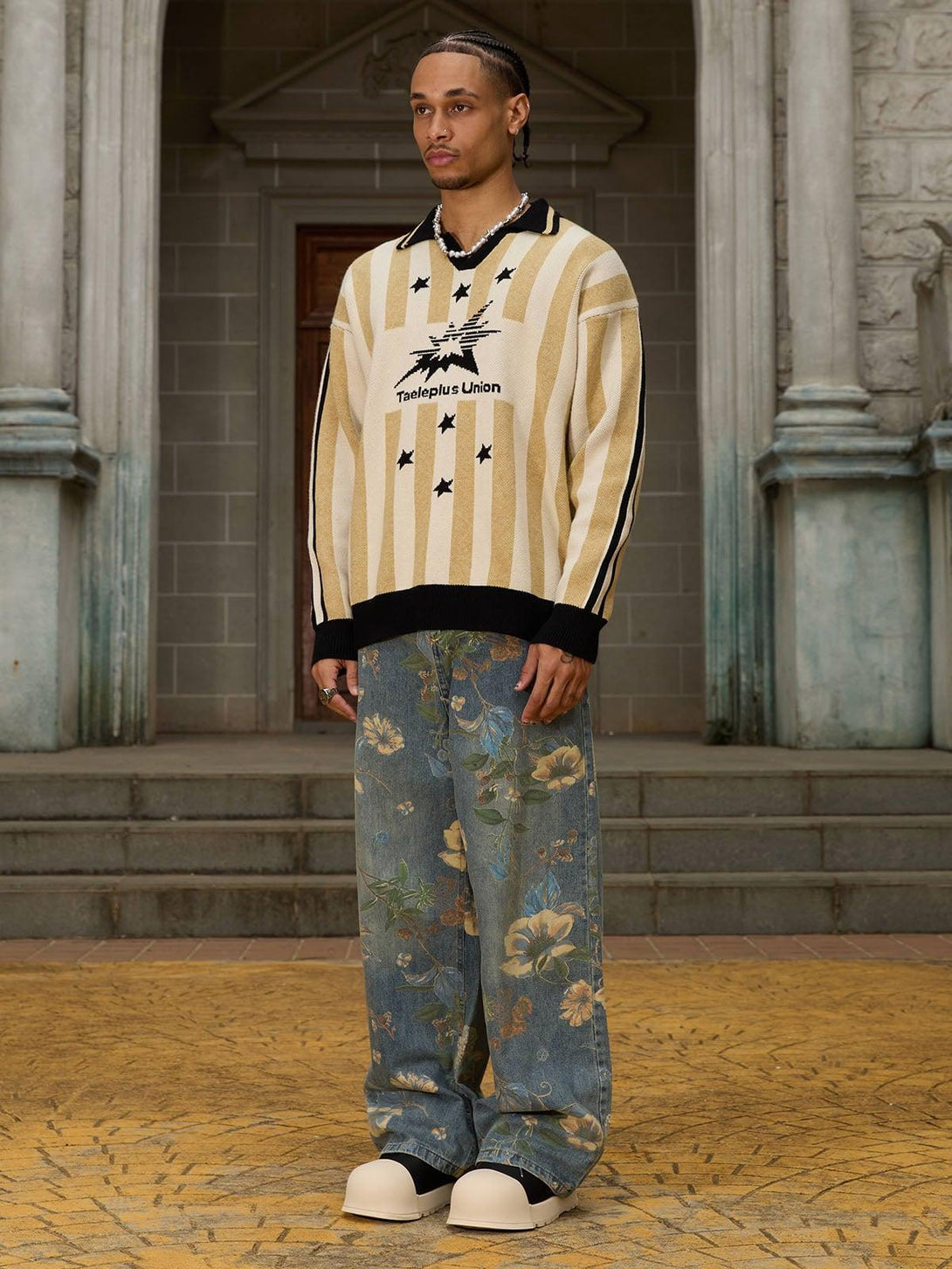 Model in a striped sweater with star design by TALISHKO, paired with floral denim pants.
