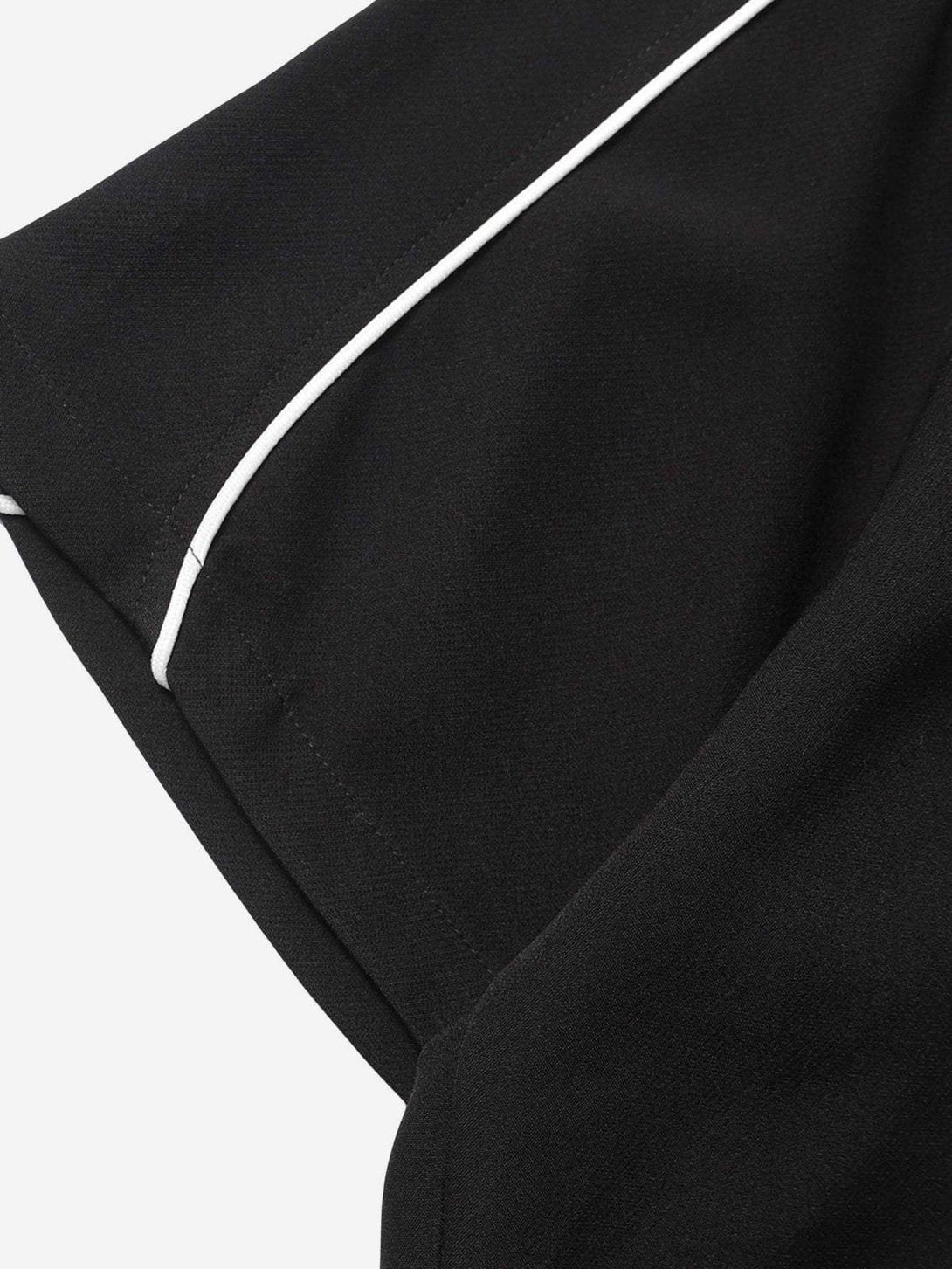 A close-up of TALISHKO's black shirt sleeve with white piping detail, emphasizing craftsmanship.