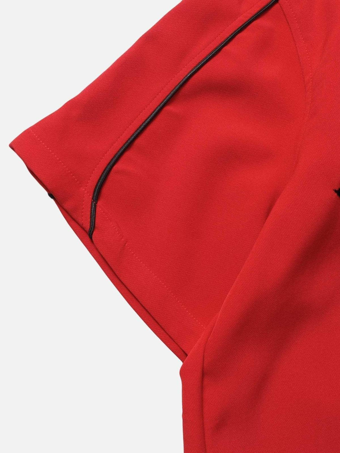 Detailed view of TALISHKO's red shirt sleeve with black piping, showcasing craftsmanship.