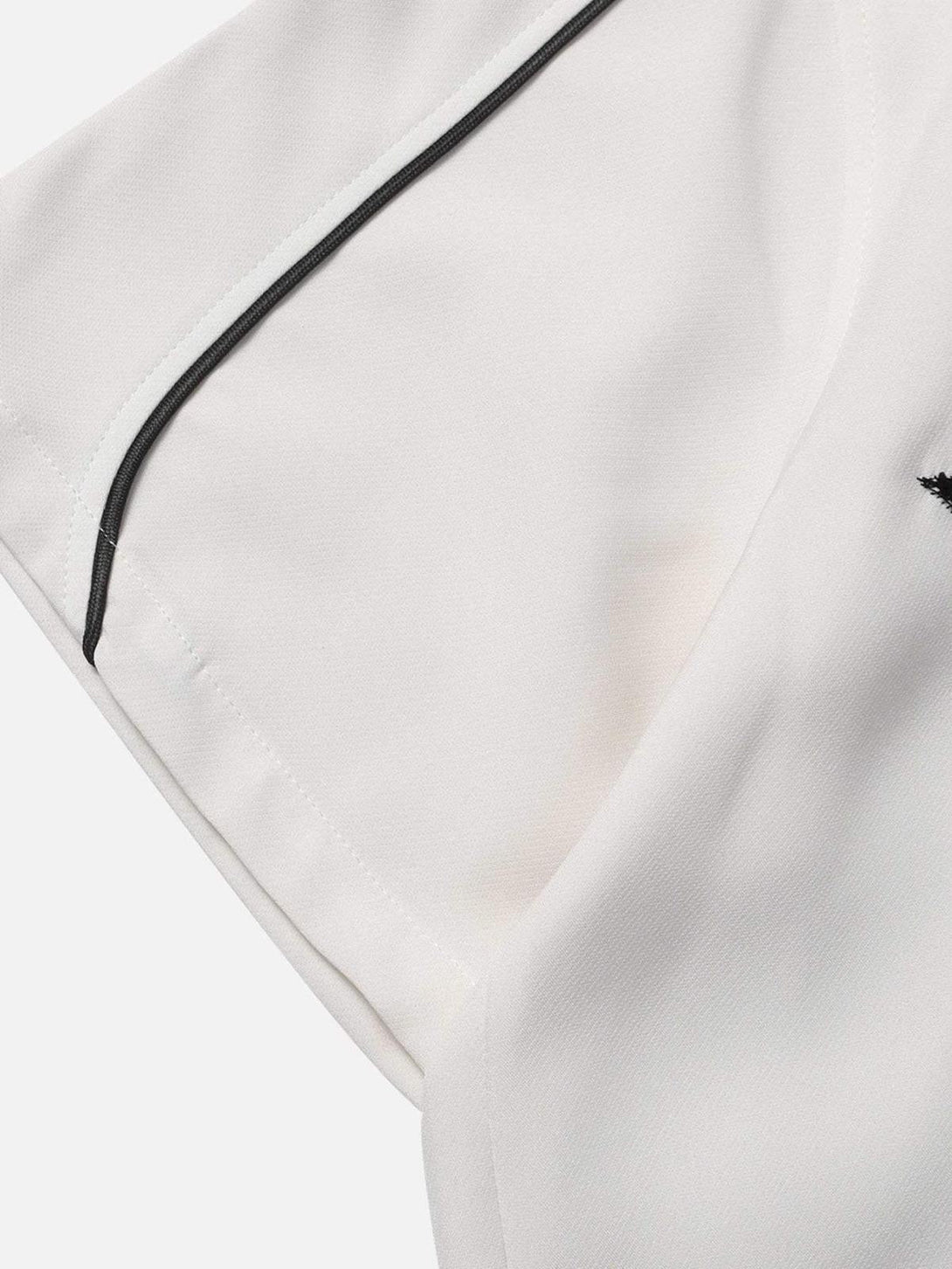 A close-up of TALISHKO's white shirt sleeve with black piping, highlighting quality craftsmanship.