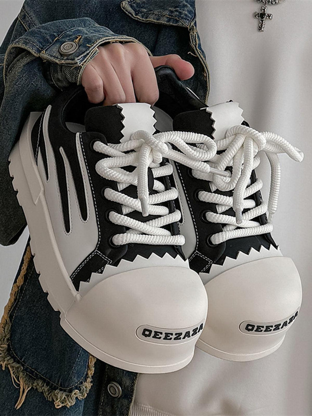 TALISHKO sneakers with bold contrast and unique design, held by a model in denim.