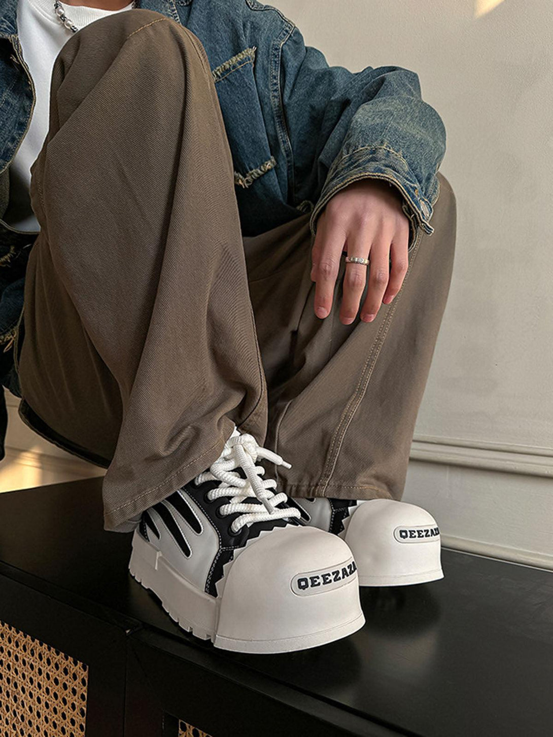 TALISHKO street sneakers in bold contrast, worn with casual brown pants and a denim jacket.